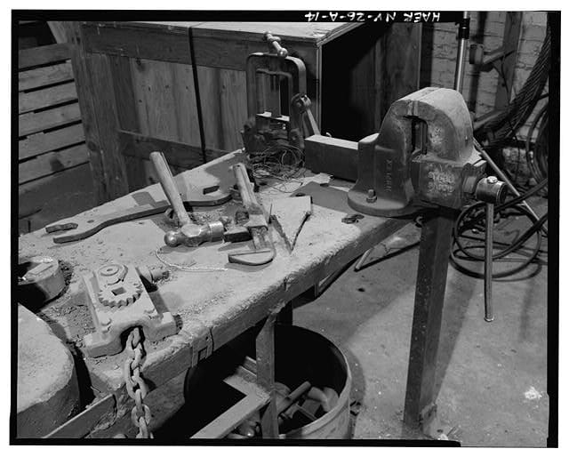 A black and white photo of an old, cluttered workbench.